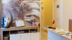 A reception area with a modern design, featuring a wall-mounted digital display, a reception desk, and a decorative wall with abstract patterns. - Partenope's house (Ercolano)