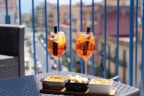 Two glasses of iced tea with lemon slices on a balcony table with a city view.