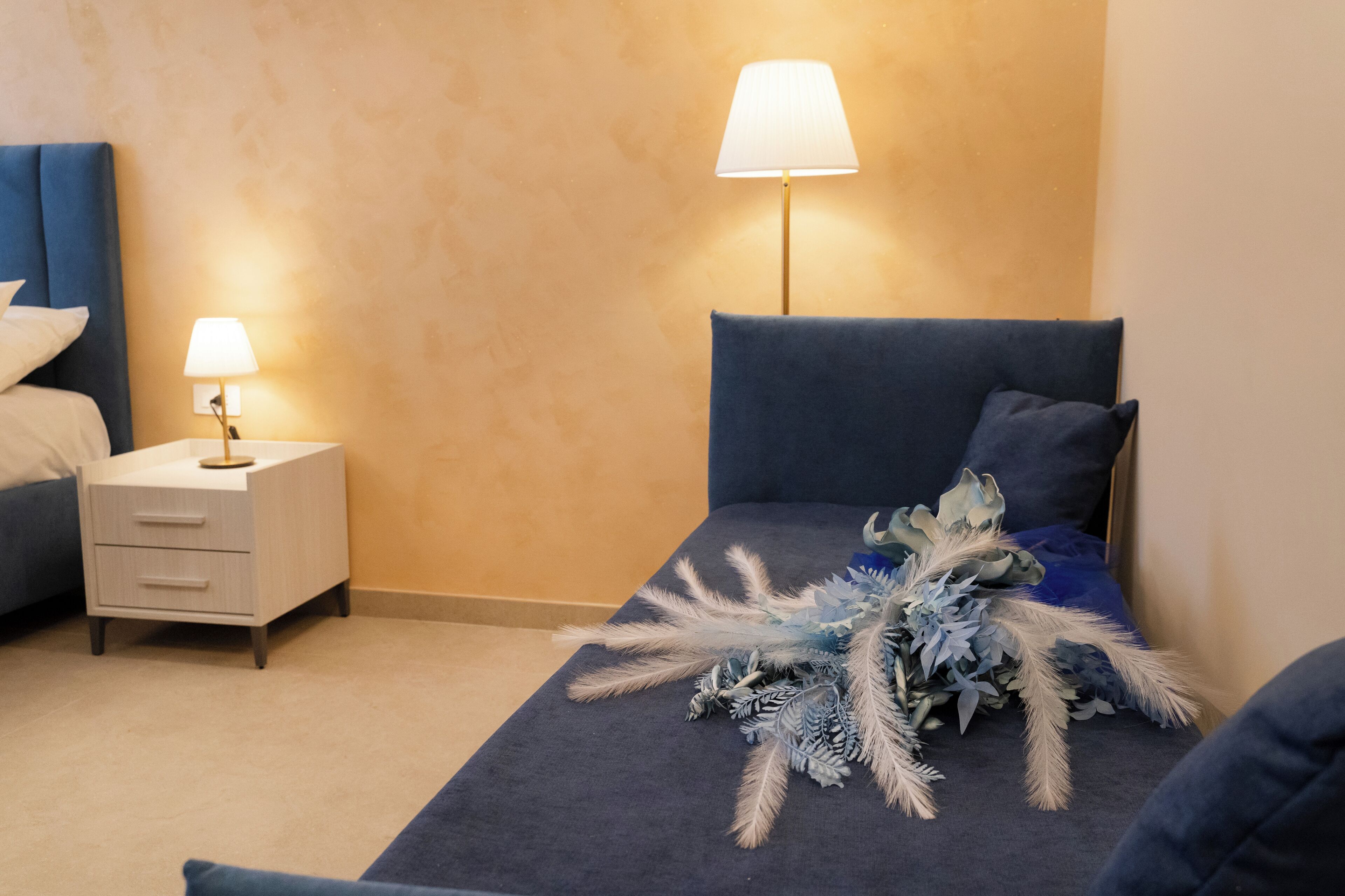 A bedroom with a bed, bedside table, lamp, and decorative pillows.