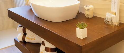A bathroom with a large white sink, a mirror, a telephone, and a small plant on the counter.