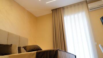 Una habitación de hotel moderna con una cama grande, cabecero y una ventana con cortinas.