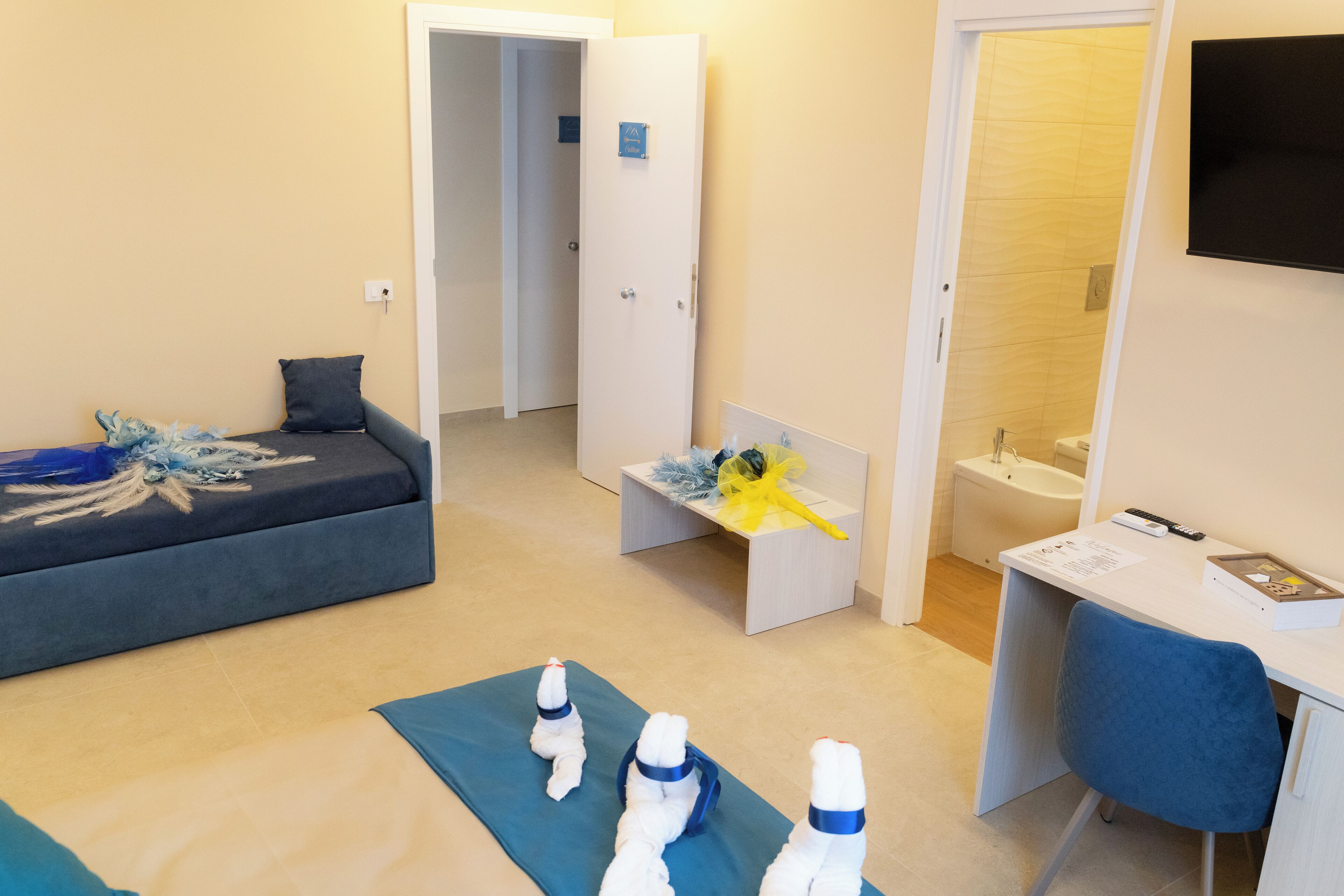 Ein Hotelzimmer mit Bett, Schreibtisch, Stuhl, Bad und Fernseher.
