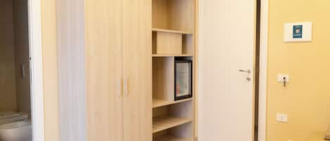 Ein Zimmer mit Holzschrank, Bett, Nachttisch und Toilette.