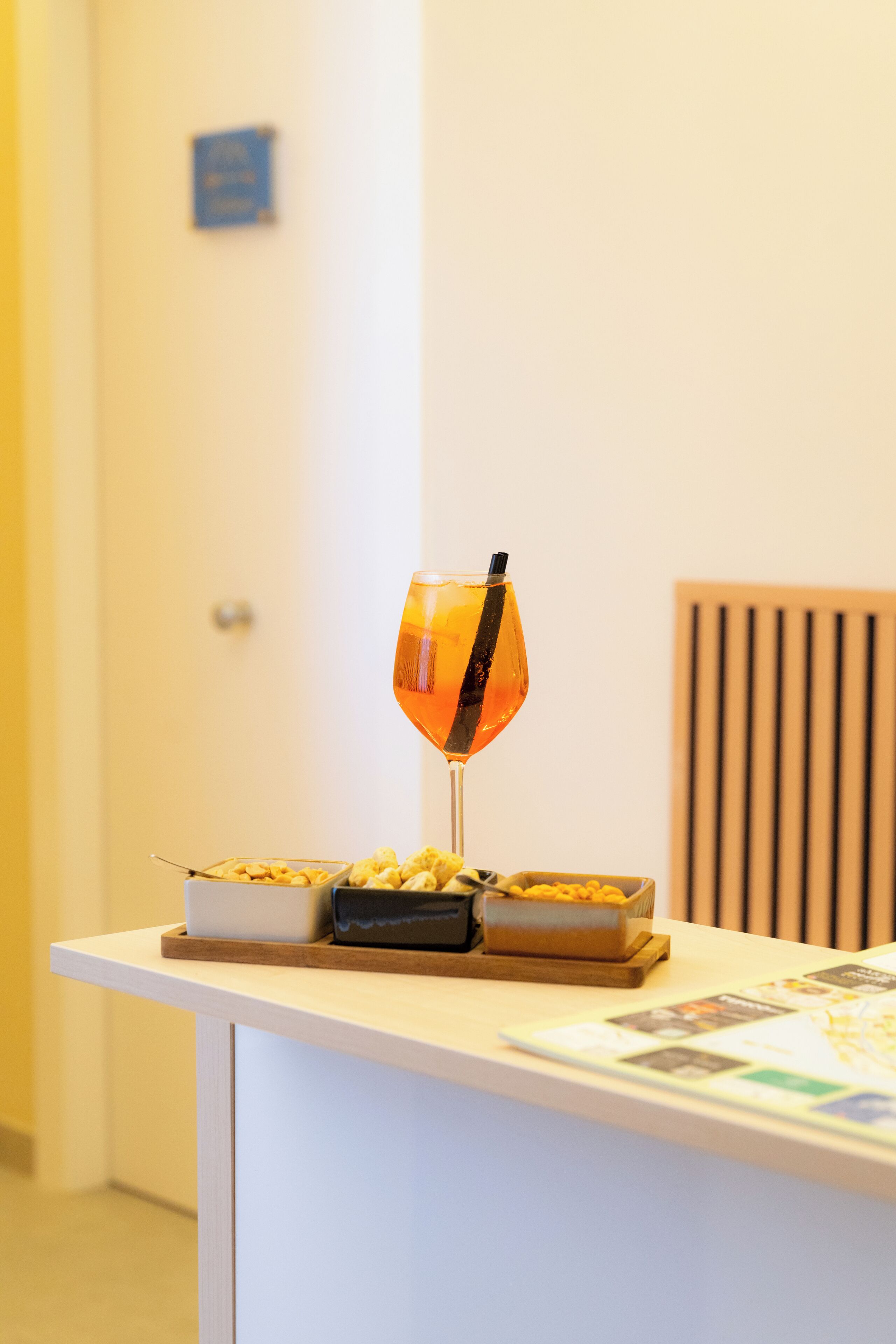 Un comptoir d’accueil avec un verre de boisson à l’orange, un bol de collations et une assiette de biscuits.