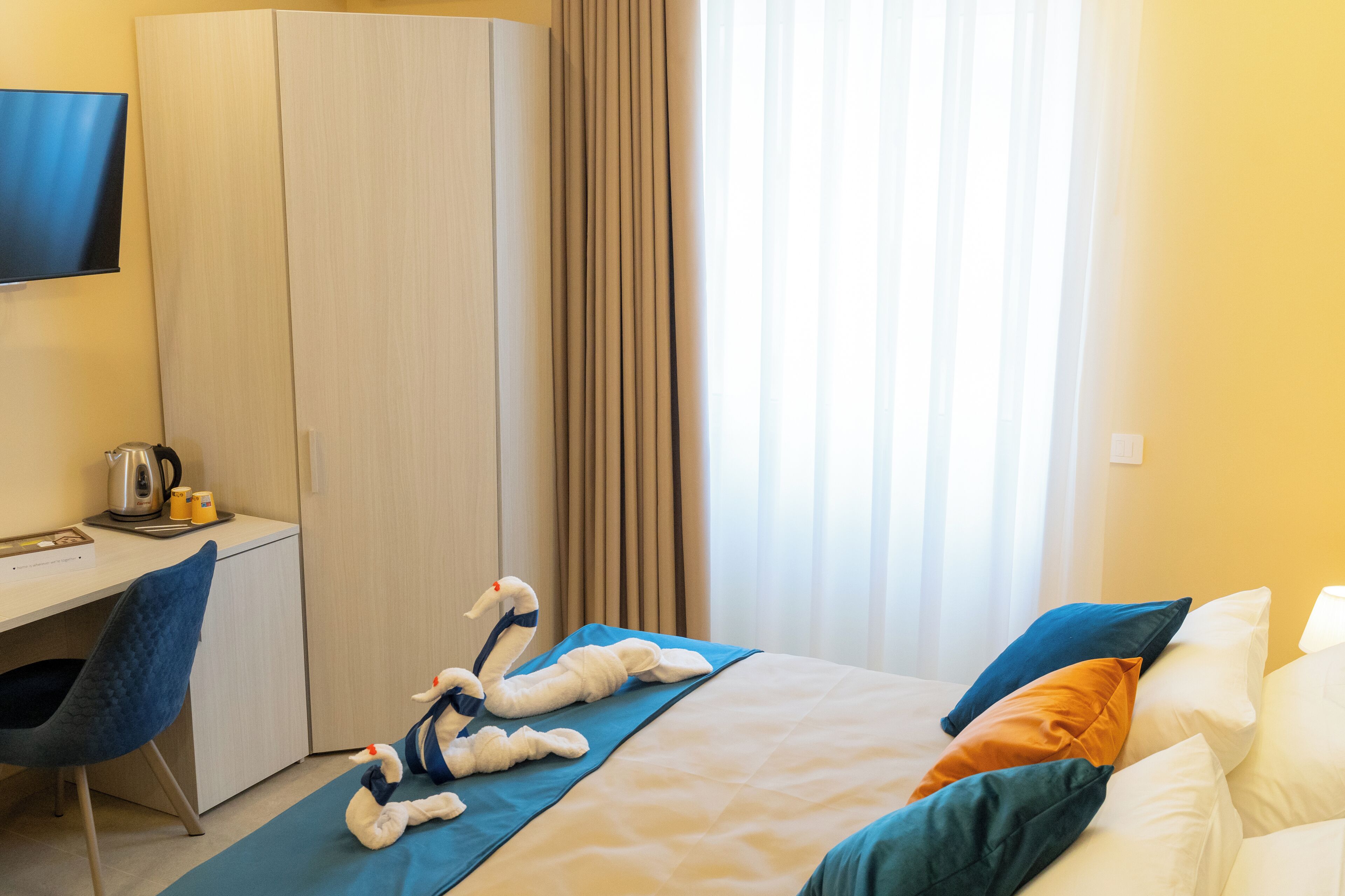 Een hotelkamer met een bed, een bureau, een stoel, een televisie en een raam met gordijnen.