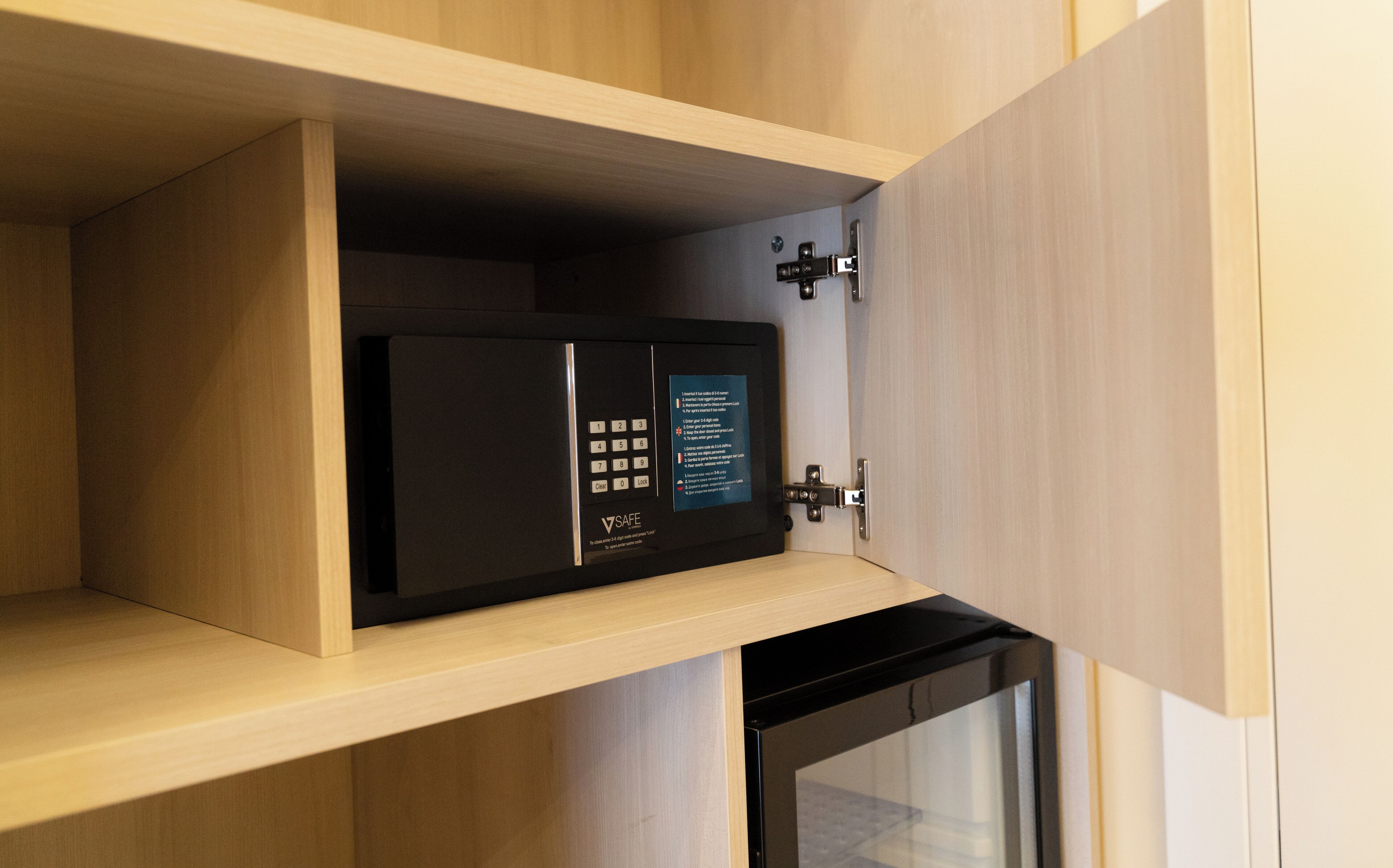 A safe with a keypad and a lock mechanism inside a wooden cabinet.