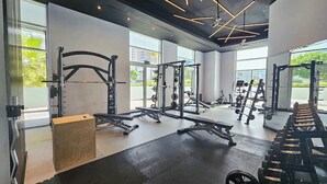 A modern gym with various weightlifting equipment, large windows, and a minimalist design. - StayShort - Stylish Barsha Heights Retreat with Swimming Pool for 2 (Barsha Heights)