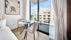 Une chambre d’hôtel moderne dotée d’une grande fenêtre, d’une table à manger et d’un fauteuil confortable.