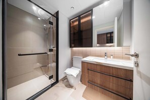 Un baño moderno con cabina de ducha de vidrio, inodoro y armarios de madera.