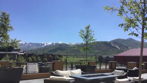 An outdoor seating area with wicker furniture and a fire pit, overlooking a mountainous landscape. - Breathtaking Views, Shopping Center Steps Away! (Park City)