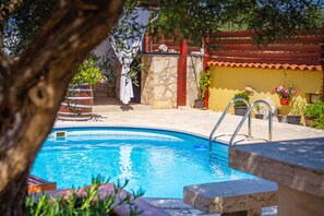 Una piscina con un muro de piedra, una valla de madera y plantas en macetas.