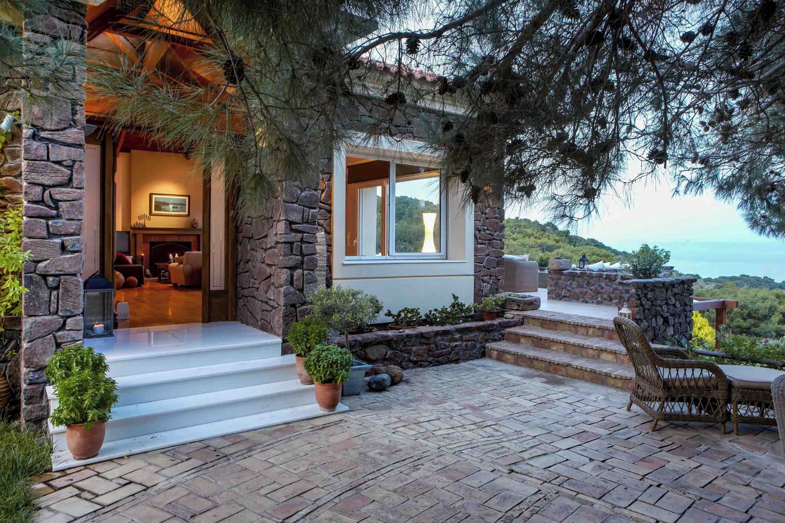 A stone house with a fireplace, outdoor seating, and a view of the landscape.
