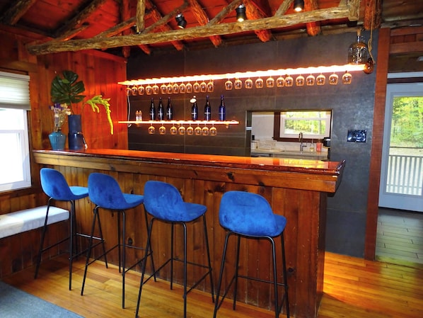 A bar area with wooden walls, a bar counter, and four blue bar stools.