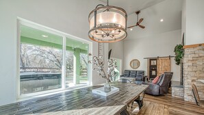 Un vaste espace de vie comprenant une grande table à manger en bois, une cheminée et une vue sur l’extérieur grâce à de grandes fenêtres.