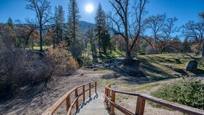 Un escalier en bois menant au sommet d’une colline, avec un ciel dégagé et des arbres en arrière-plan.