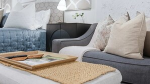 Un saló modern amb un sofà gris, un llit blau i una taula auxiliar negra.