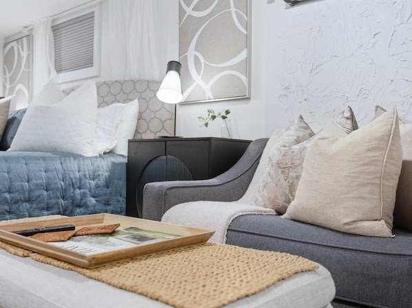 Ein modernes Wohnzimmer mit einem grauen Sofa, einem blauen Bett und einem schwarzen Beistelltisch.