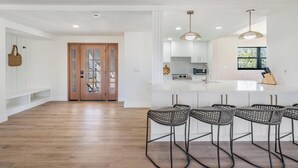 A modern kitchen with white cabinets, a large island, and bar stools. - NEW! Waterfront + Sauna + Pool + Pet Friendly +Gym (Anna Maria)