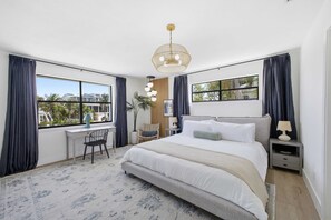 Un dormitorio con una cama grande, un escritorio y vistas al exterior.