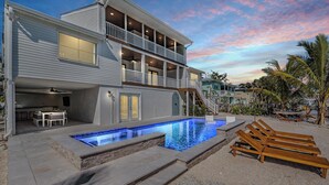 A two-story house with a swimming pool, outdoor seating, and a balcony. - NEW! Waterfront + Sauna + Pool + Pet Friendly +Gym (Anna Maria)