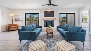 A spacious living room with a fireplace, two sofas, a coffee table, and a ceiling fan. - NEW! Waterfront + Sauna + Pool + Pet Friendly +Gym (Anna Maria)
