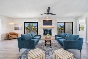 A spacious living room with a fireplace, two sofas, a coffee table, and a ceiling fan.