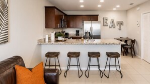 A modern kitchen with a central island, bar stools, a dining area, and a ceiling fan. - Family & Pet Friendly-Sleeps 4 (Apollo Beach)
