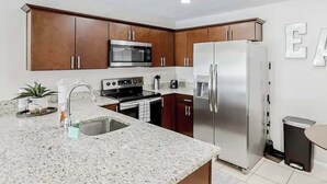 A modern kitchen with granite countertops, stainless steel appliances, and wooden cabinets. - Family & Pet Friendly-Sleeps 4 (Apollo Beach)