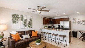 A modern kitchen with dark wood cabinets, a stainless steel refrigerator, and a bar area with stools. - Family & Pet Friendly-Sleeps 4 (Apollo Beach)