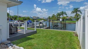 A marina with boats docked, a grassy area, and a clear sky.