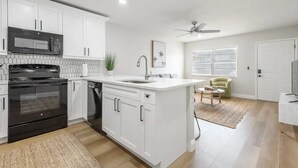 A modern kitchen with white cabinets, a black stove, and a microwave.
