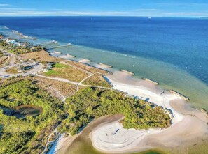 An aerial view of a coastal area with a beach, a pier, and a small settlement with buildings and roads. - Waterfront-Family & Pet Friendly for 6 (Apollo Beach)