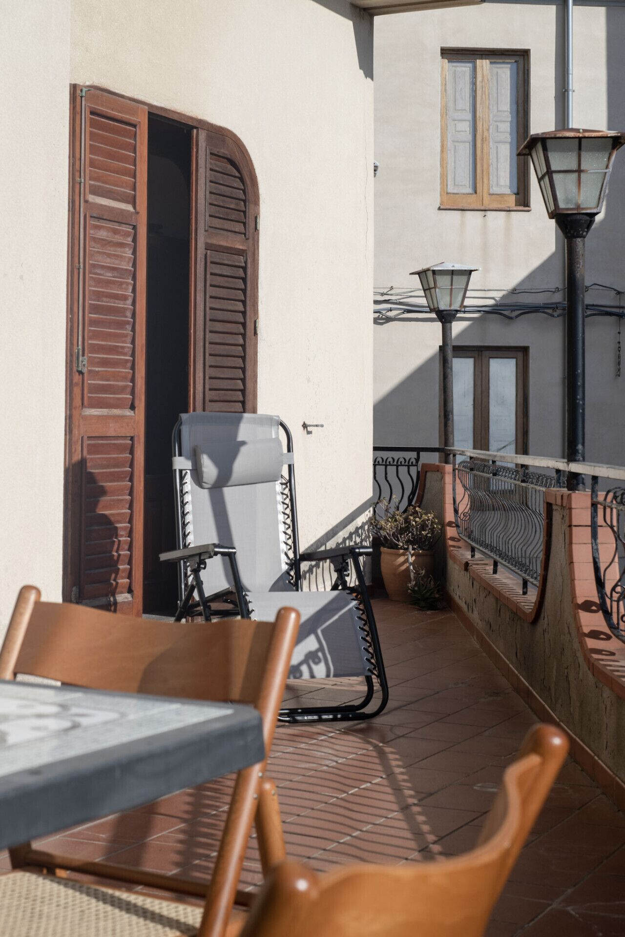An outdoor seating area with a table and chairs, a potted plant, and a railing.