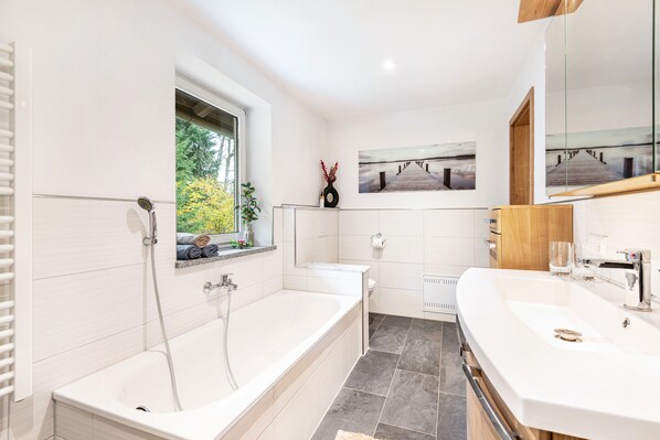 A modern bathroom with a bathtub, a shower, a toilet, and a sink.