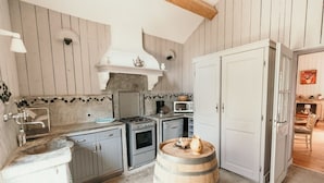 A kitchen with a stove, microwave, and sink. There is a wooden barrel in the center. - Chateau Sainte Cecile (Saint-Thibery)