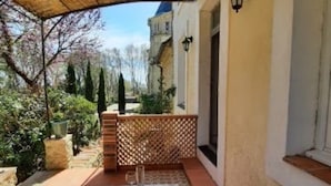An outdoor dining area with a table set for four, a wicker basket, and a bottle. - Chateau Sainte Cecile (Saint-Thibery)