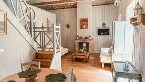 A spacious living area with a wooden staircase, a fireplace, and a dining table with chairs. - Chateau Sainte Cecile (Saint-Thibery)