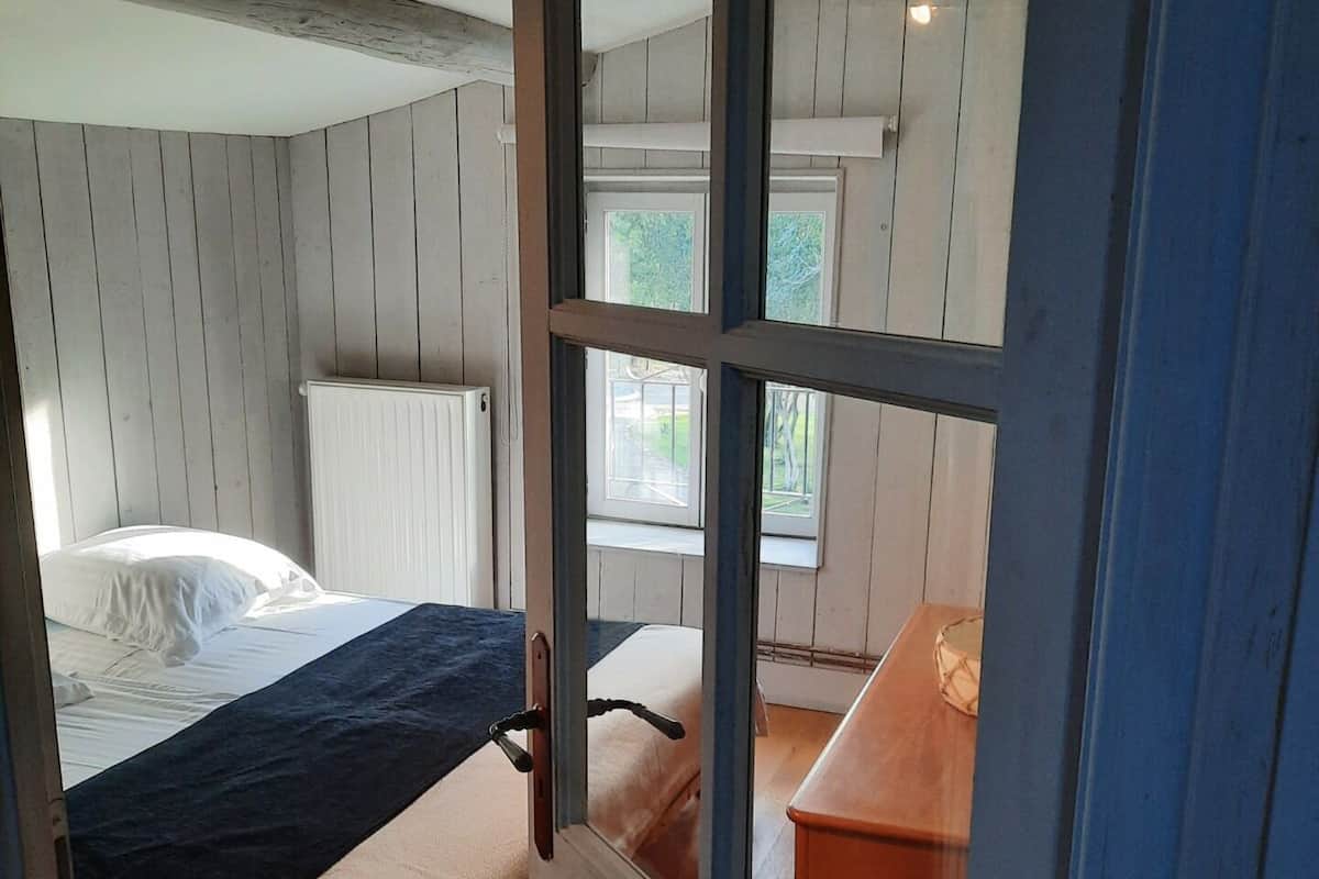 A bedroom with a bed, a dresser, and a window.
