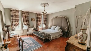 A bedroom with a large bed, a chair, a desk, and a vase. - Chateau Sainte Cecile (Saint-Thibery)