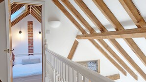 Une chambre avec un plafond en pente, un mur en briques et un lit blanc.