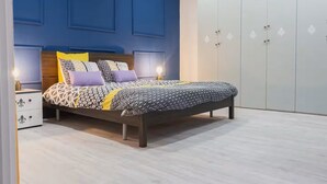 Ein Schlafzimmer mit Bett, Nachttischen, einem Kleiderschrank und einer blauen Wand.