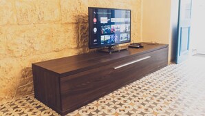 Ein dunkles Holz-TV-Möbel mit einem Flachbildfernseher, der eine Streaming-Oberfläche zeigt.