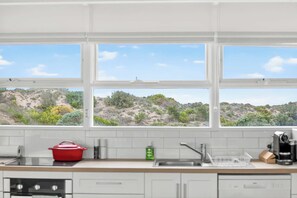 A kitchen with a view of a hilly landscape through large windows.