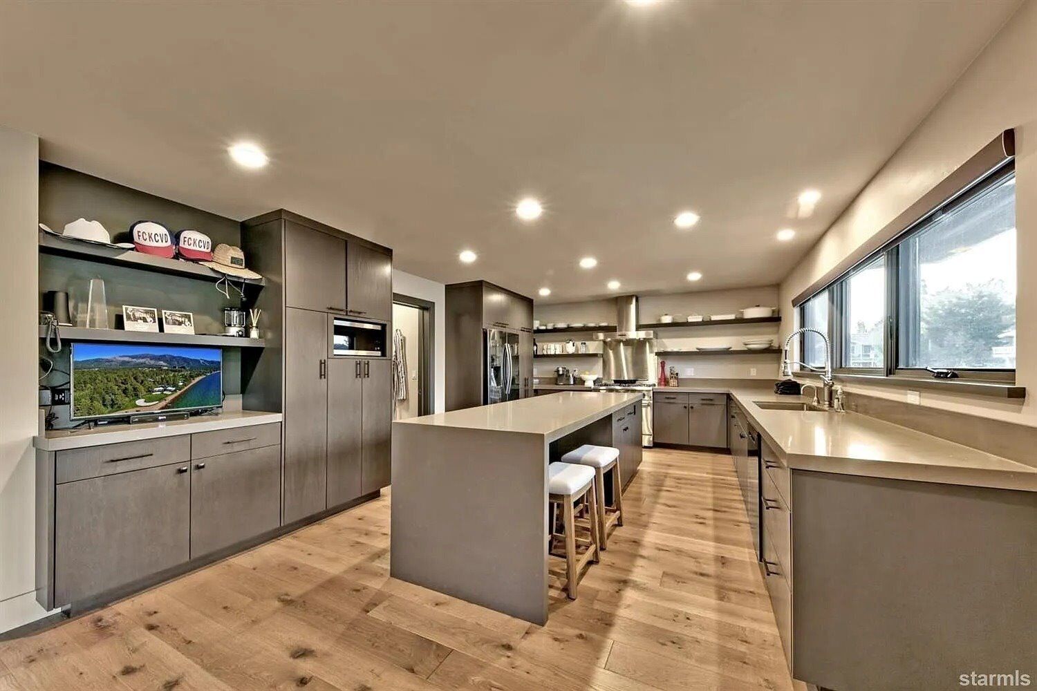 A modern kitchen with a central island, built-in appliances, and a large window providing natural light.