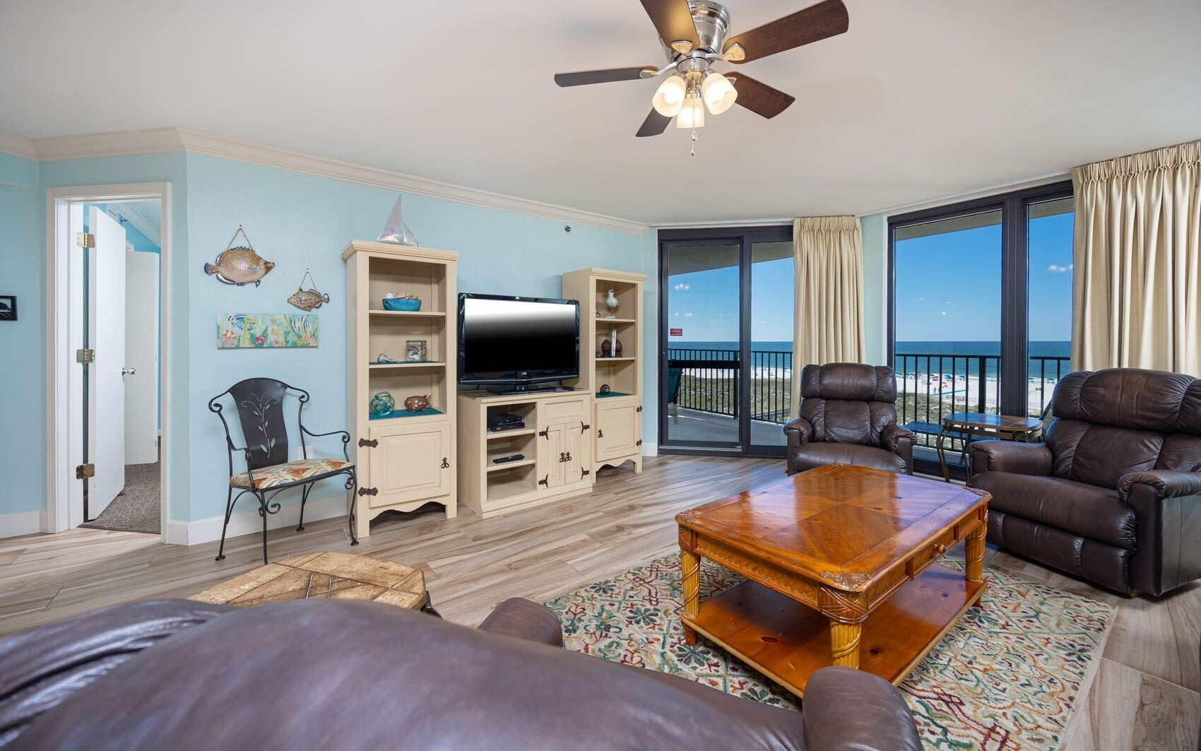 Amplia sala de estar con un televisor grande, muebles de cuero y un balcón con vistas.