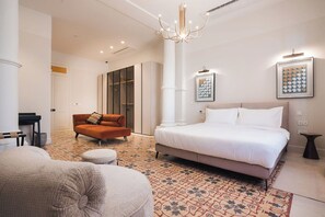 A bedroom with a large bed, a sofa, a chair, and a small table.