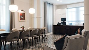 Moderni hotellihuone, jossa on ruokailutila, keittiö ja oleskelualue, josta on näkymä.