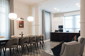 A modern hotel room with a dining area, a kitchen, and a seating area with a view.