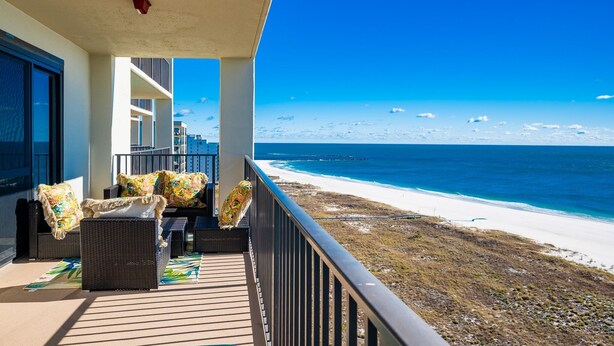 Ein Balkon mit Korbmöbeln und Blick auf den Strand.