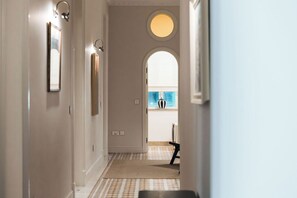 A hallway with a checkered floor, a round window, and a door leading to a room with a blue wall and a white object.
